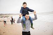 Portrait playful father carrying son on shoulders