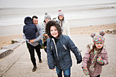 Happy family in warm clothing walking up beach ramp