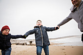 Playful father and sons on winter ocean beach