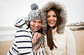 Portrait mother and daughter in warm clothing on beach