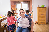 Portrait smiling boy in wheelchair at home
