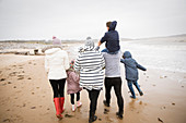 Family in warm clothing walking on winter ocean beach