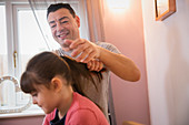 Boy brushing hair of daughter in bathroom