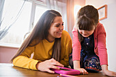 Happy sisters using digital tablet at table
