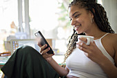 Woman drinking coffee and using smart phone