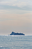 Iceberg in distance on tranquil Atlantic Ocean Greenland