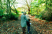 Mother and son walking in idyllic autumn park