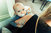 Portrait cute baby girl with pacifier in mother arms