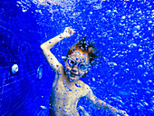 Portrait playful boy swimming underwater