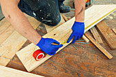 Construction worker measuring and marking floorboard