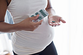 Close up pregnant woman taking vitamins