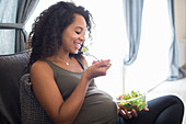 Happy pregnant woman eating salad
