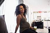 Happy pregnant woman drinking green smoothie