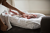 Mother reaching for newborn baby son in bassinet