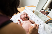 Mother changing diaper of newborn baby son