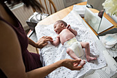 Mother changing diaper of newborn baby son