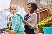 Pregnant woman and daughter hanging laundry