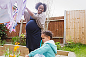 Pregnant woman with daughter hanging laundry