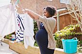 Pregnant woman hanging laundry on clothesline