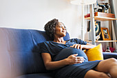 Serene pregnant woman relaxing on sofa