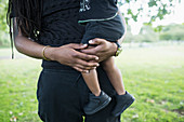 Father holding toddler son in park