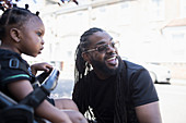 Happy father with long braids and toddler son on sidewalk