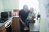 Portrait happy father and toddler son in apartment kitchen