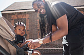 Father with long braids fastening toddler son in stroller