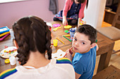 Portrait boy with Down Syndrome colouring with siblings