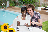 Couple using digital tablet at poolside patio