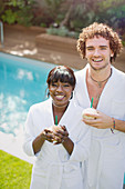 Portrait happy couple in bathrobes drinking from coconuts