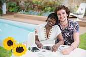 Portrait happy multiethnic couple at poolside