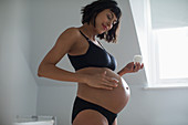 Pregnant woman applying moisturizer to stomach