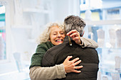 Smiling senior woman hugging husband in jewelry store