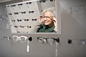Senior woman trying on eyeglasses in optometry shop