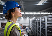 Confident female supervisor looking up in factory