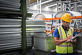 Male worker with clipboard working in steel factory