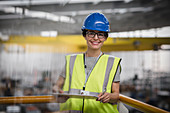 Confident female worker with clipboard in factory