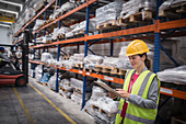 Female worker with clipboard checking inventory in warehouse
