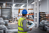 Male supervisor with paperwork walking in warehouse