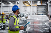 Male supervisor with paperwork walking in factory