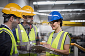 Supervisors with clipboard talking on platform in factory