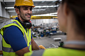 Male supervisor talking to coworker on platform in factory