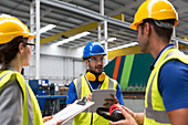 Supervisor and workers with clipboard and tablet in factory