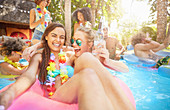 Young women friends drinking and playing in swimming pool