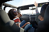 Playful young women enjoying road trip in jeep