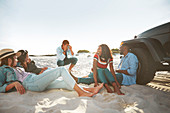 Young man photographing friends hanging out on sunny beach