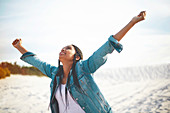 Exuberant young woman with arms outstretched on beach