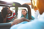 Smiling young friends talking, enjoying road trip in jeep