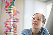 Pensive girl students examining DNA model in classroom